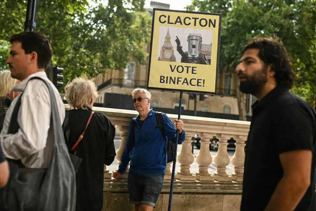 Un homme brandit une pancarte « Clacton Vote Binface »